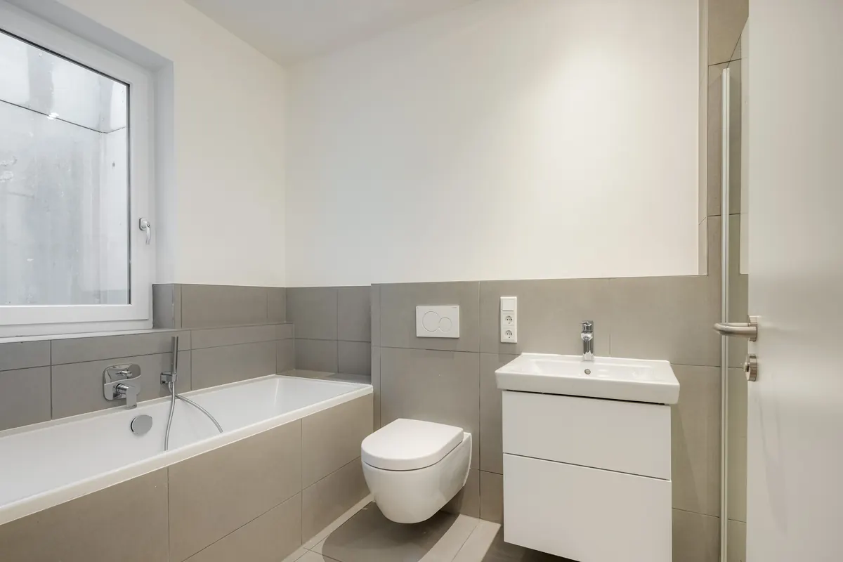 Bad mit Wanne und grau-weißen Fliesen