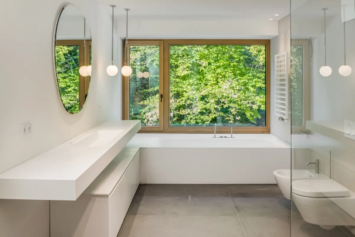 Bad mit Wanne vor einem großen Fenster zum Wald