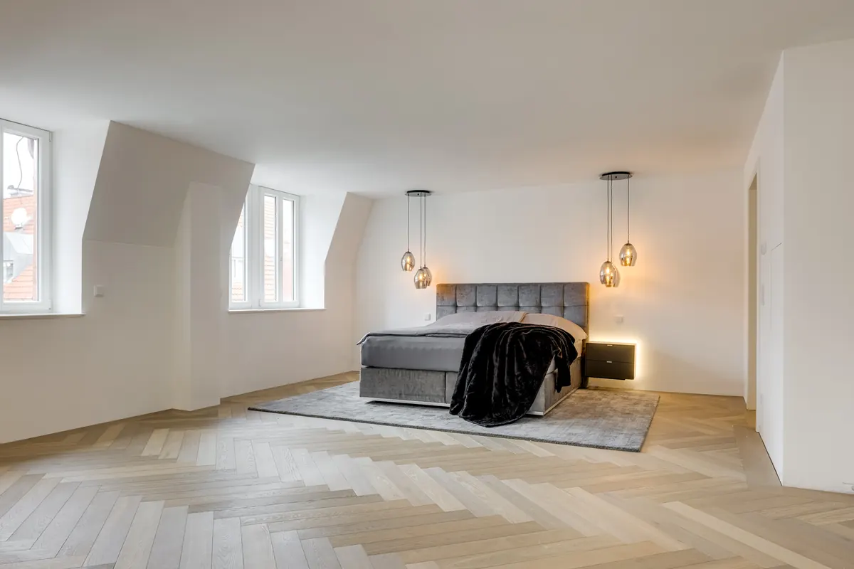 Schlafzimmer unter dem Dach mit Fischgrätparkett und Pendelleuchten