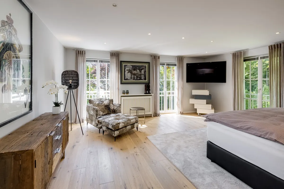 Schlafzimmer mit Sessel, Eichenparkett und bodentiefen Fenstern