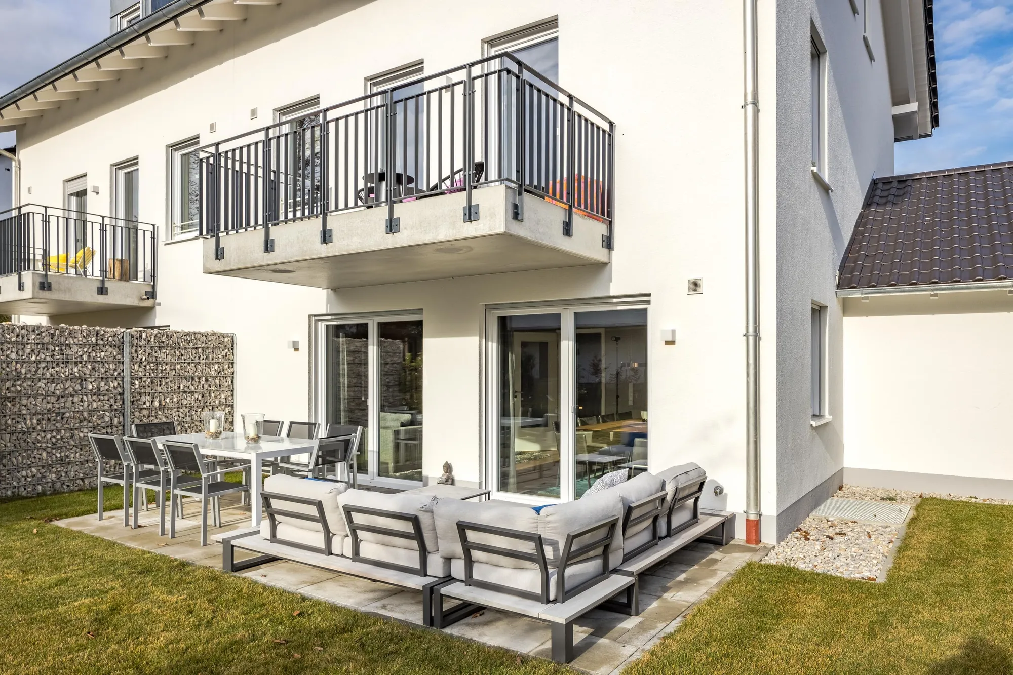 Terrasse mit Lounge-Möbeln vor bodentiefen Fenstern