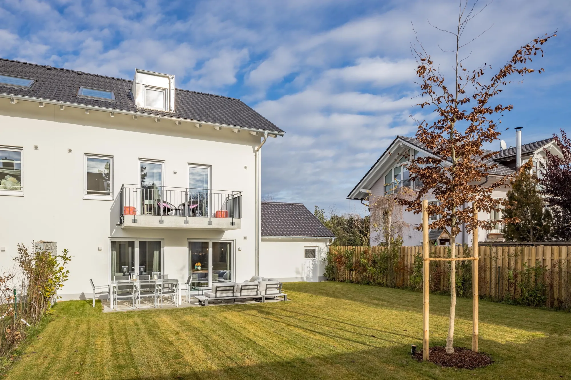 Gartenseite mit jungem Baum und Holzzaun