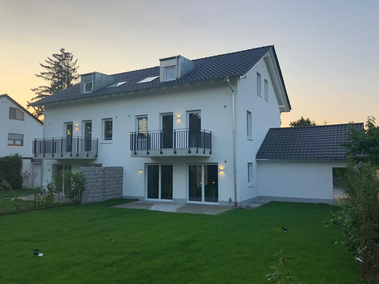 Haus in der Abenddämmerung mit Rasen und Balkonen
