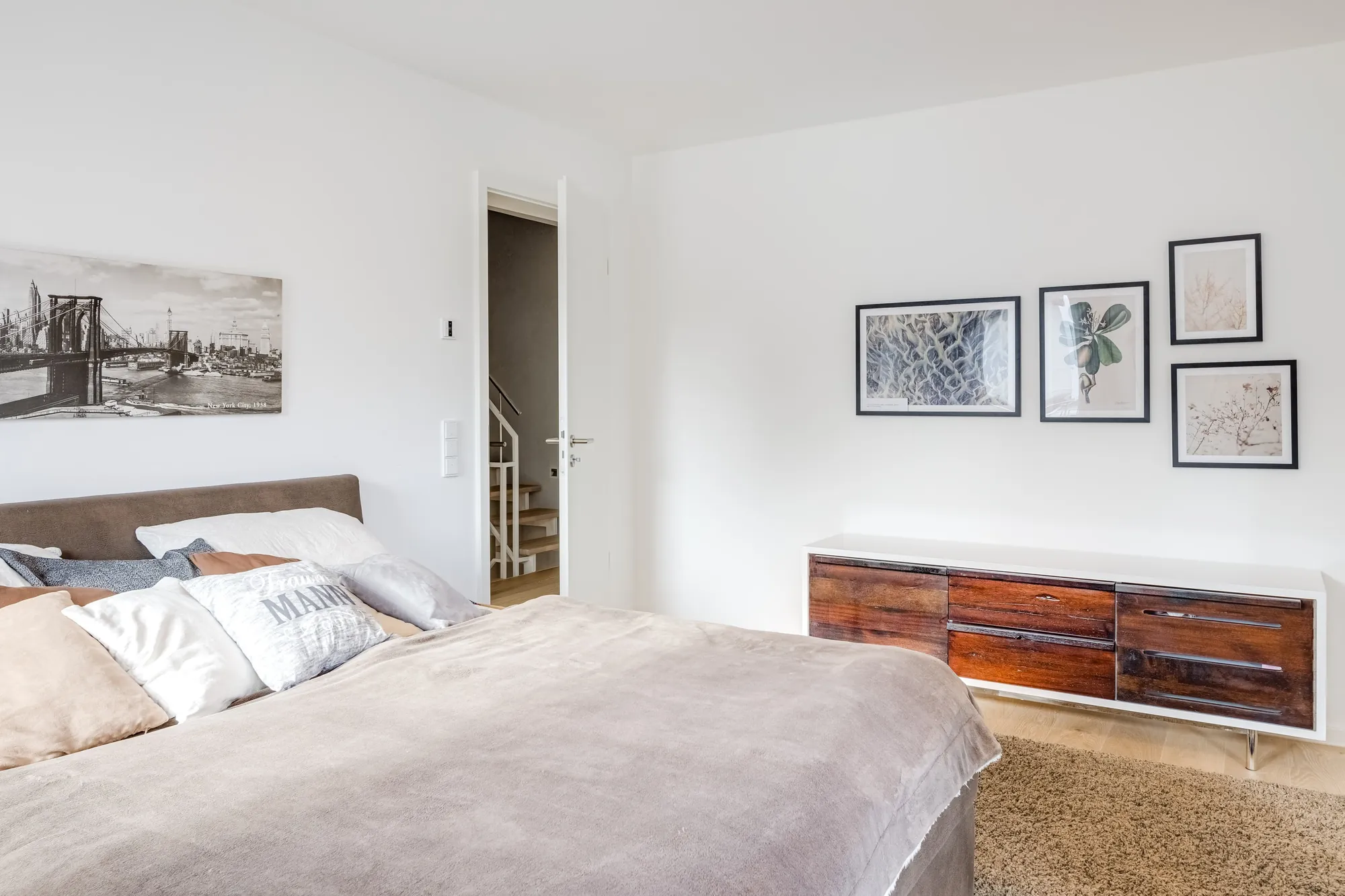 Schlafzimmer mit Bilderwand und Holzsideboard