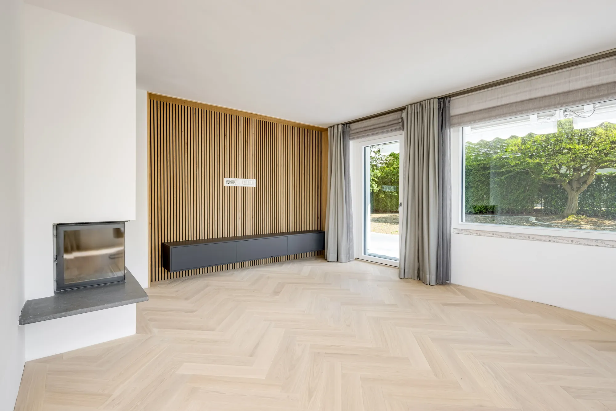 Kaminwand mit Holzlamellen und bodentiefem Fenster