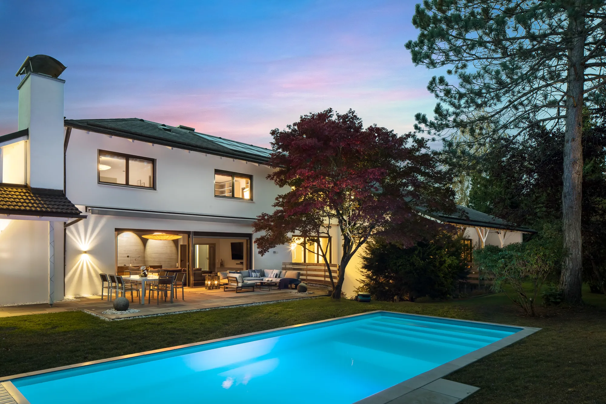 Villa mit beleuchtetem Pool und Terrasse in der Abenddämmerung
