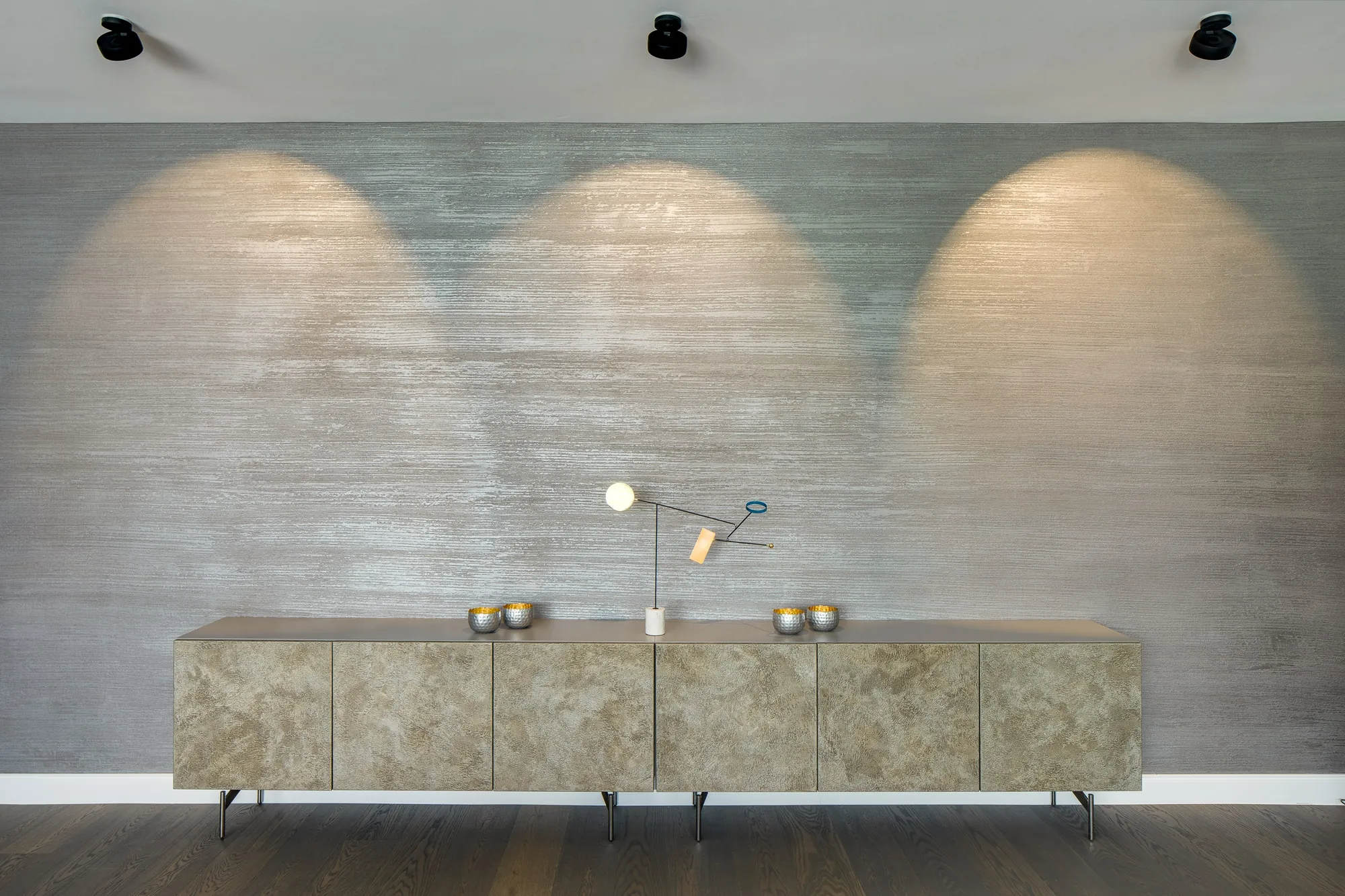 Sideboard vor strukturierter Wand mit Lichtkegeln