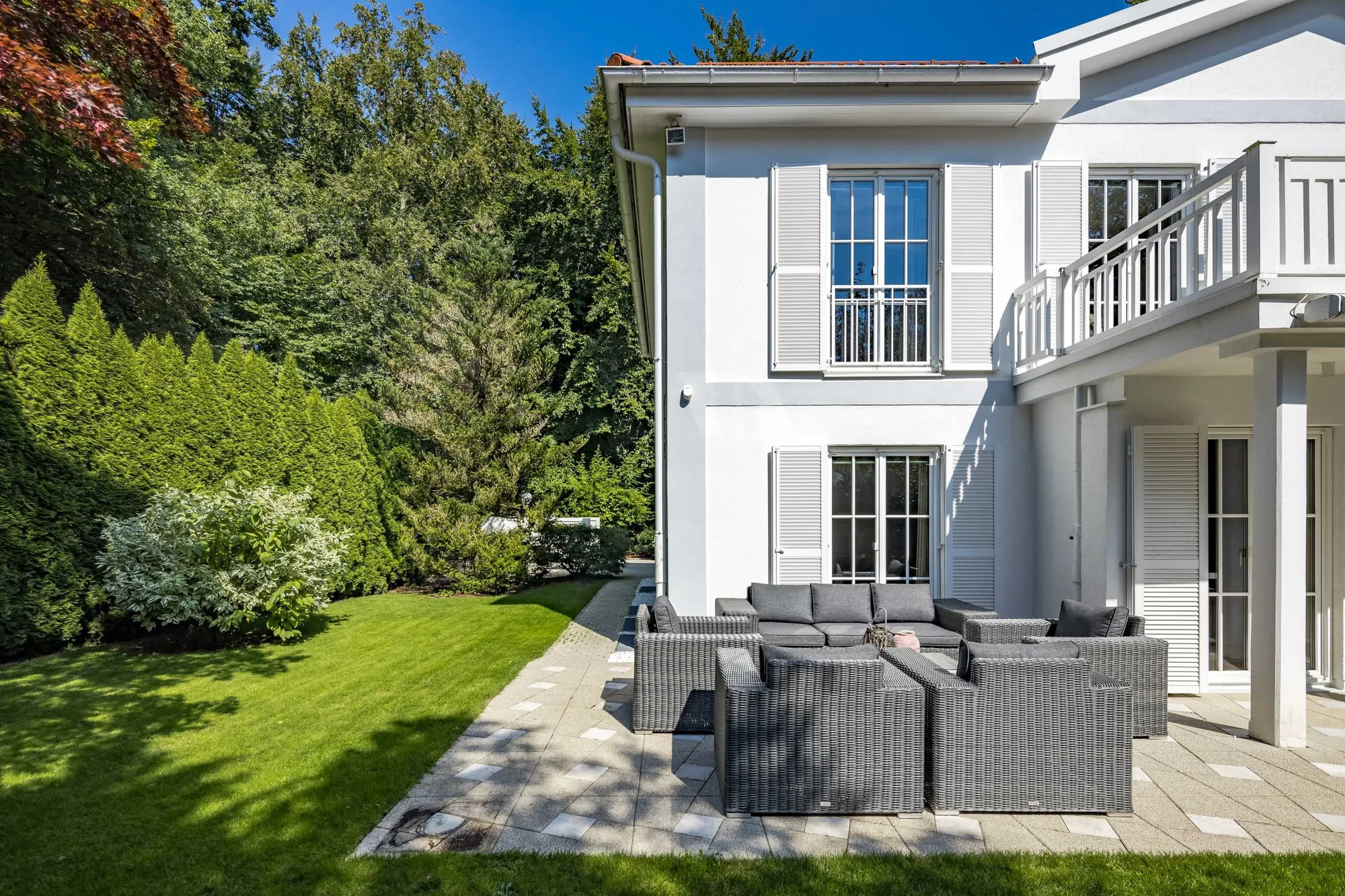 Seitenansicht mit Balkon und Lounge im Garten