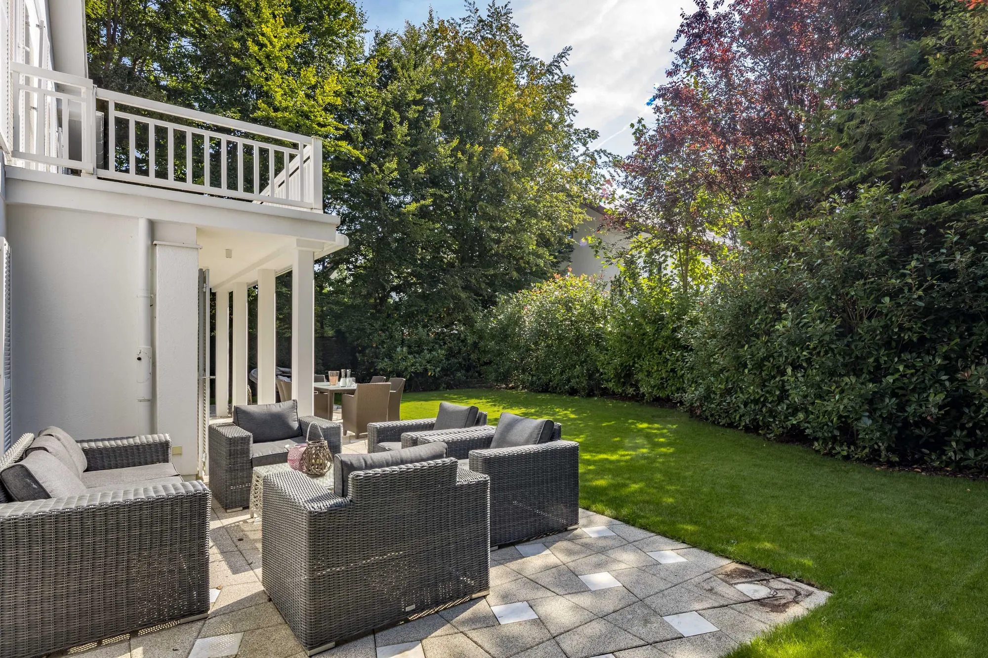 Terrasse mit Rattan-Lounge und Blick in den Garten