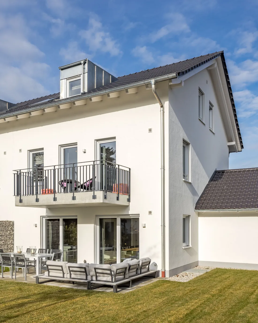 Weißes Doppelhaus mit Gauben und Garage in der Seitenansicht