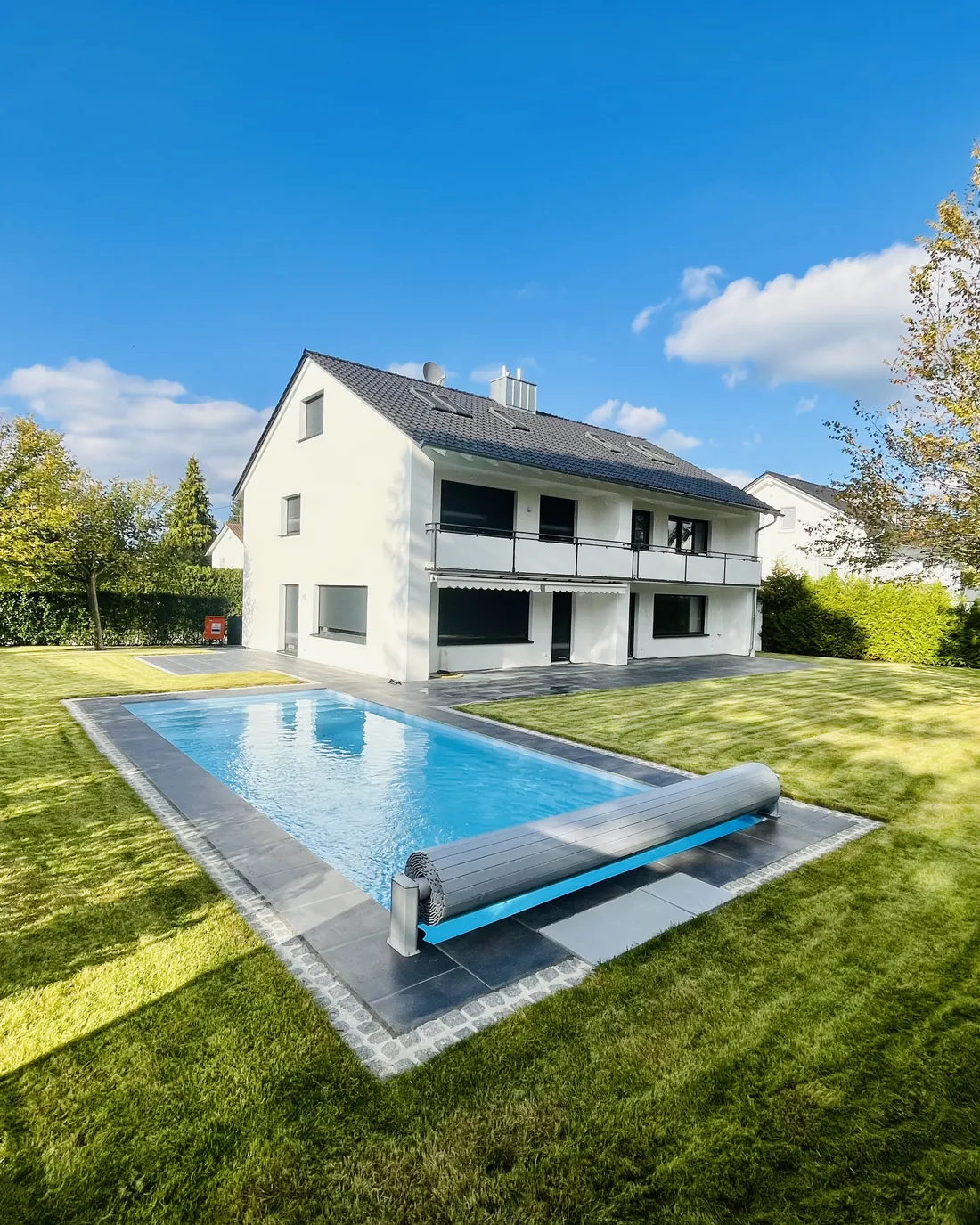 Weißes Haus mit Pool im sonnigen Garten